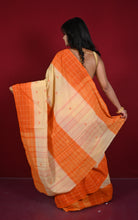 A woman wearing a peach and orange checkered saree, shown from behind against a solid dark red background.