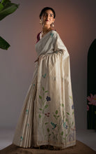 Side view of cream soft Jamdani saree highlighting the lower border with deer and floral hand-woven artwork.