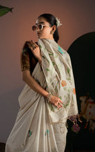 Close up shot of cream Jamdani saree pallu edge with amber orange flowers and green leaves paired with brown blouse.