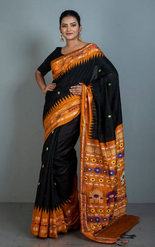 Woman wearing a black and orange saree with a kotiki patterned border against a gray background